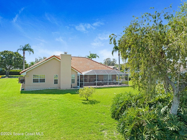 back of property featuring a lanai and a lawn