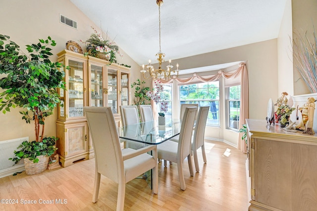 dining room with light hardwood / wood-style flooring, high vaulted ceiling, and a notable chandelier