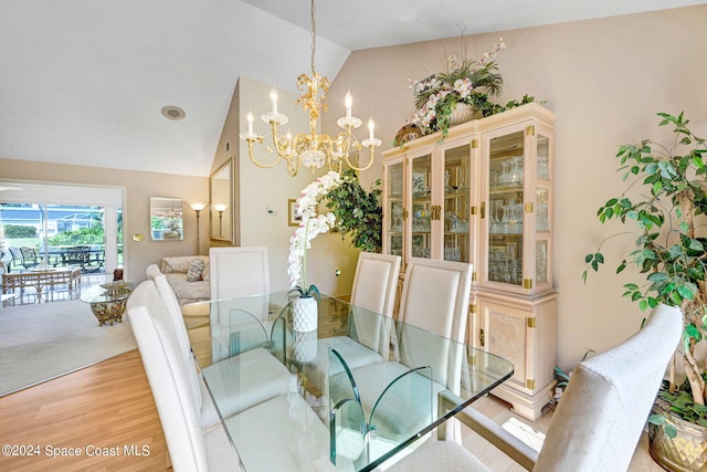 dining space with hardwood / wood-style flooring, lofted ceiling, and a notable chandelier