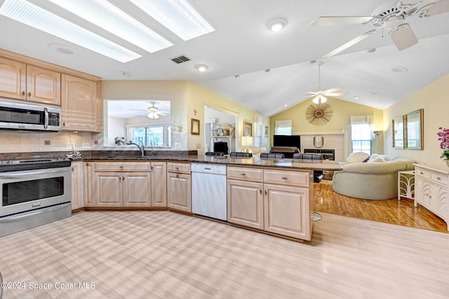 kitchen featuring sink, lofted ceiling, light brown cabinetry, appliances with stainless steel finishes, and light wood-type flooring