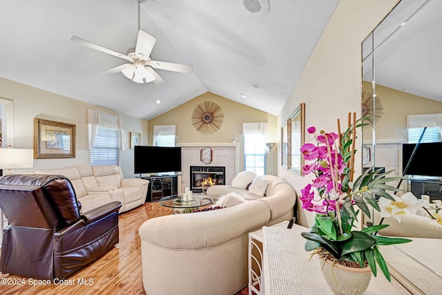 living room with vaulted ceiling, ceiling fan, light hardwood / wood-style floors, and plenty of natural light