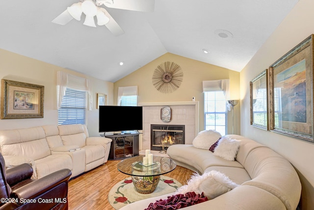 living room with ceiling fan, a fireplace, lofted ceiling, and light wood-type flooring