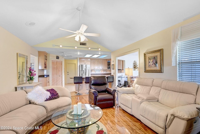 living room featuring light wood-type flooring, vaulted ceiling, and ceiling fan