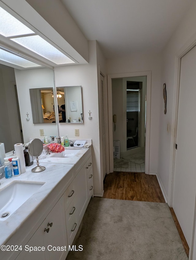 bathroom with hardwood / wood-style floors, vanity, a skylight, and ceiling fan