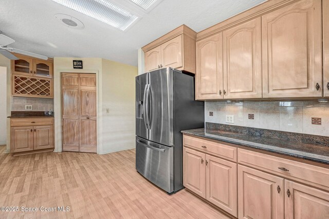 818 Spanish Wells Dr, Melbourne, FL 32940 - kitchen with dark stone counters, light brown cabinets, decorative backsplash, light wood-style floors, and stainless steel fridge