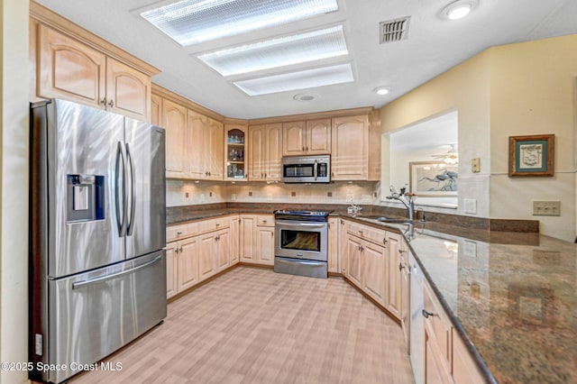 818 Spanish Wells Dr, Melbourne, FL 32940 - kitchen featuring dark stone counters, a sink, light brown cabinetry, glass insert cabinets, and appliances with stainless steel finishes