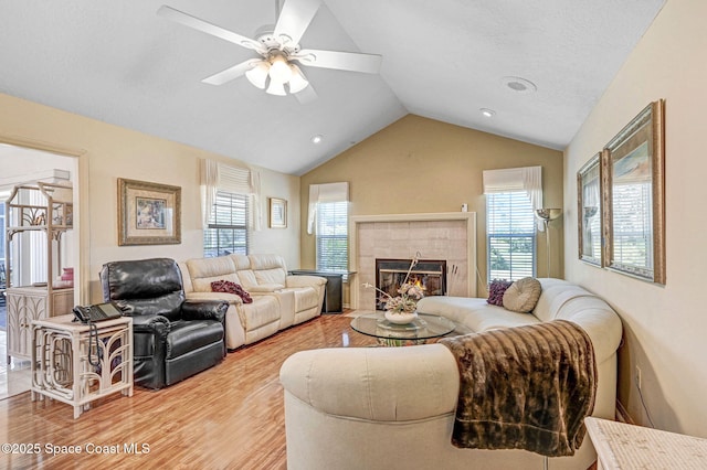 818 Spanish Wells Dr, Melbourne, FL 32940 - living room featuring ceiling fan, vaulted ceiling, a tile fireplace, and light wood-style flooring