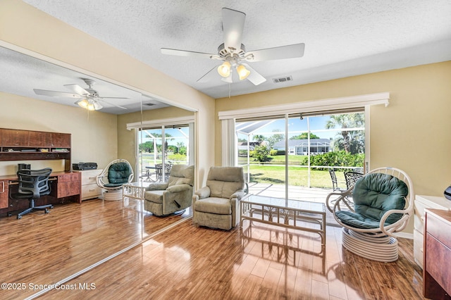 818 Spanish Wells Dr, Melbourne, FL 32940 - living room featuring a ceiling fan, a textured ceiling, and light wood-style flooring