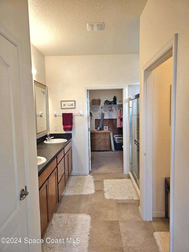 bathroom with a textured ceiling, walk in shower, and vanity