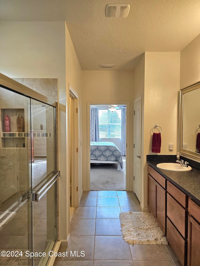 bathroom featuring vanity, tile patterned floors, a shower with door, and a textured ceiling