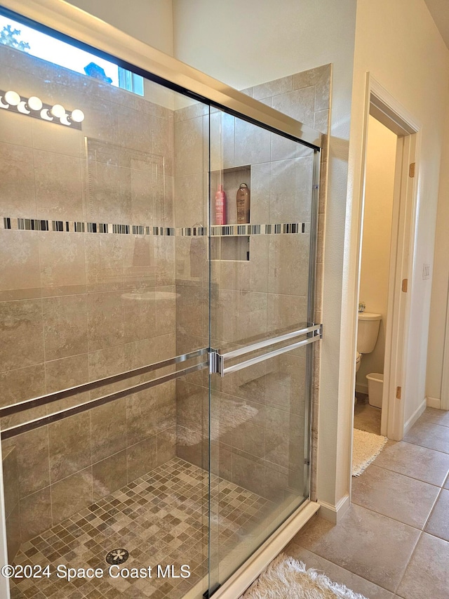 bathroom with toilet, tile patterned flooring, and a shower with shower door