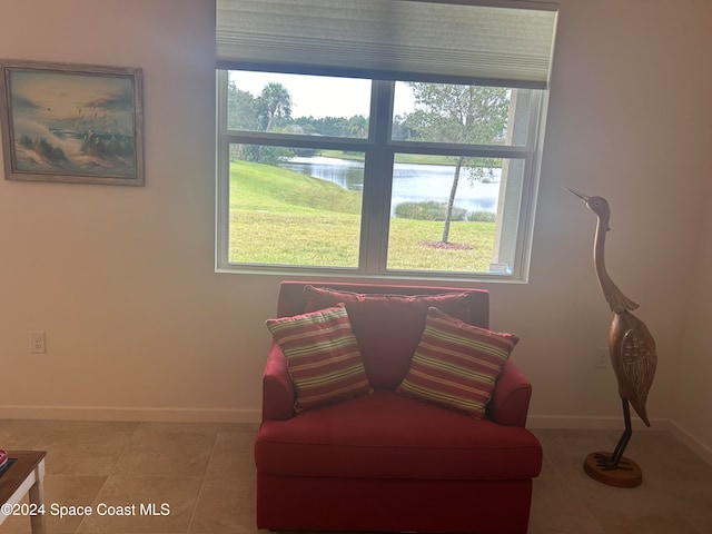 sitting room featuring a water view, a healthy amount of sunlight, and light tile patterned floors