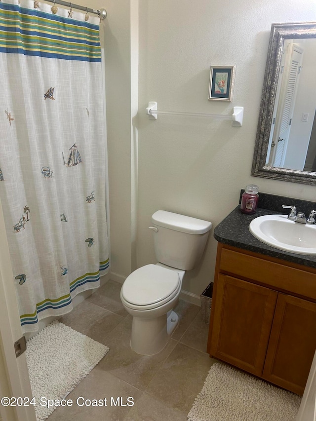 bathroom with toilet, vanity, tile patterned floors, and walk in shower