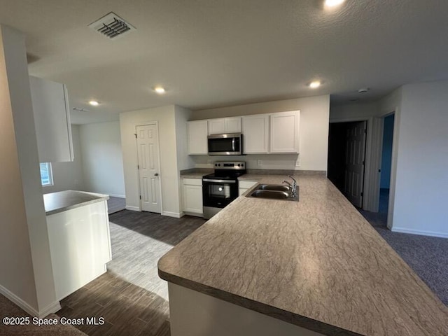 kitchen with kitchen peninsula, white cabinetry, sink, and appliances with stainless steel finishes