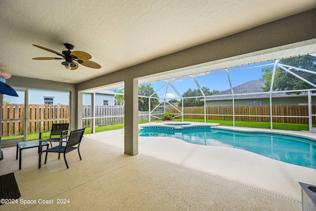 view of pool with glass enclosure, an in ground hot tub, ceiling fan, and a patio