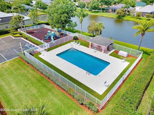 view of swimming pool featuring a patio, a water view, and a yard