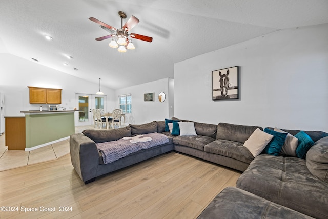 living room with vaulted ceiling, light hardwood / wood-style floors, ceiling fan, and a textured ceiling