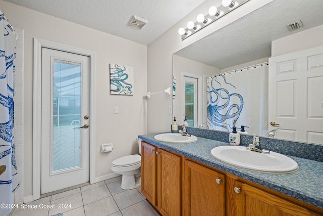 bathroom with vanity, a wealth of natural light, toilet, and tile patterned floors