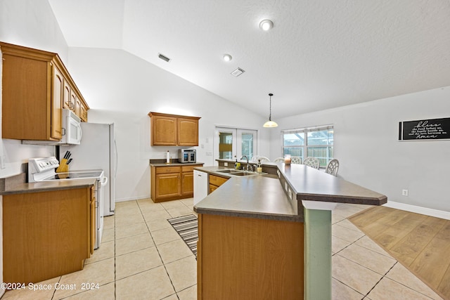 kitchen with light tile patterned flooring, sink, range, lofted ceiling, and a center island with sink