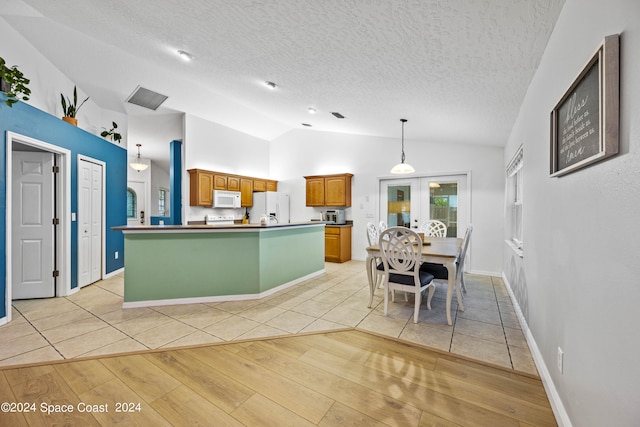 kitchen with pendant lighting, light wood-type flooring, a textured ceiling, vaulted ceiling, and white appliances