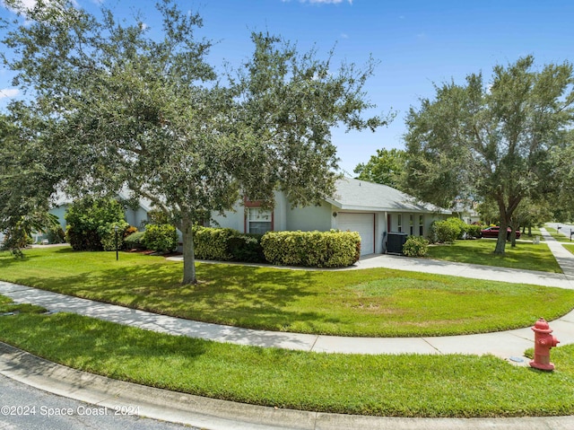 view of front of house with cooling unit, a garage, and a front yard