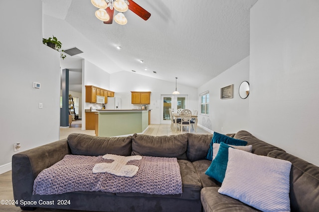 living room with light wood-type flooring, a textured ceiling, lofted ceiling, and ceiling fan