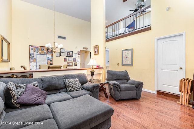 living room with a high ceiling, ceiling fan with notable chandelier, and hardwood / wood-style floors