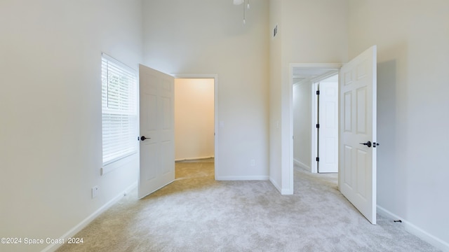 unfurnished bedroom with a high ceiling and light colored carpet