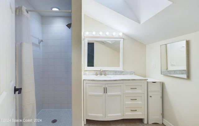 bathroom featuring vanity, a tile shower, and lofted ceiling