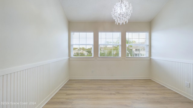 empty room with light hardwood / wood-style flooring, an inviting chandelier, and plenty of natural light