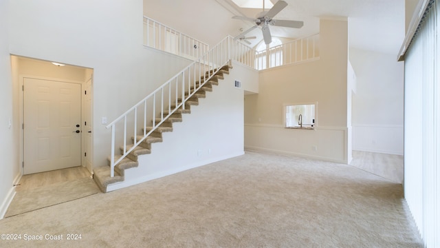 interior space with carpet, a towering ceiling, and ceiling fan