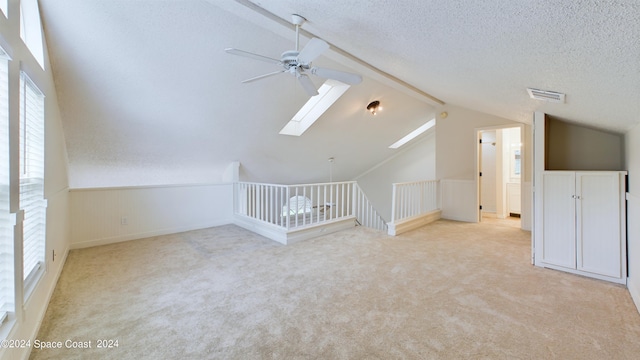 bonus room with ceiling fan, a textured ceiling, a wealth of natural light, and lofted ceiling with skylight