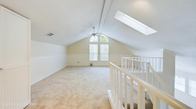 additional living space featuring light carpet, a textured ceiling, vaulted ceiling, and ceiling fan