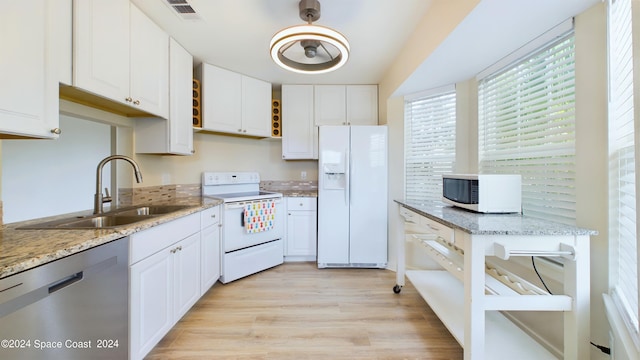 kitchen with light hardwood / wood-style floors, white cabinets, sink, and white appliances