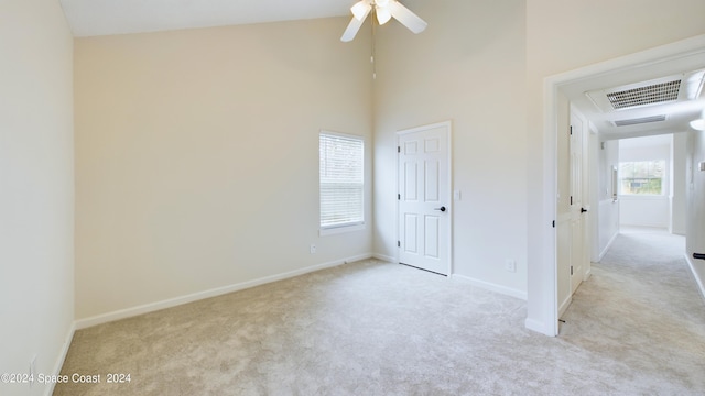 carpeted empty room featuring a high ceiling and ceiling fan