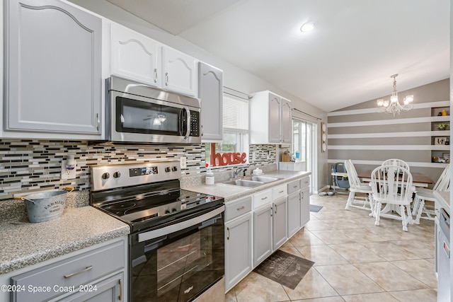 kitchen with pendant lighting, sink, stainless steel appliances, vaulted ceiling, and decorative backsplash