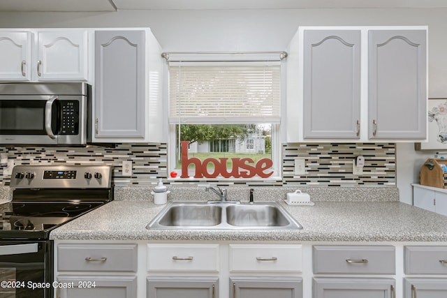 kitchen featuring white cabinets, appliances with stainless steel finishes, backsplash, and sink