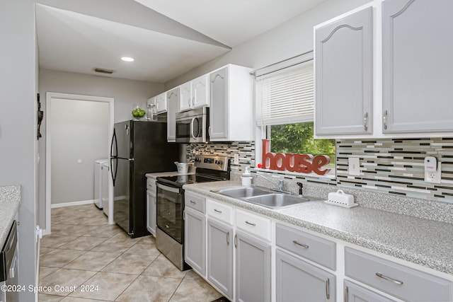 kitchen with appliances with stainless steel finishes, decorative backsplash, light tile patterned flooring, and white cabinets