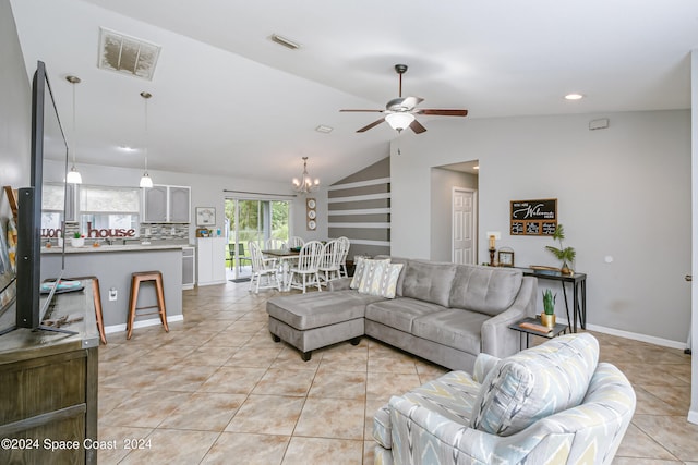 tiled living room with ceiling fan with notable chandelier and lofted ceiling