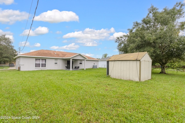 rear view of house with a storage shed, a yard, and central air condition unit