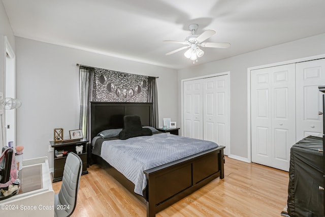 bedroom featuring ceiling fan, multiple closets, and light hardwood / wood-style floors