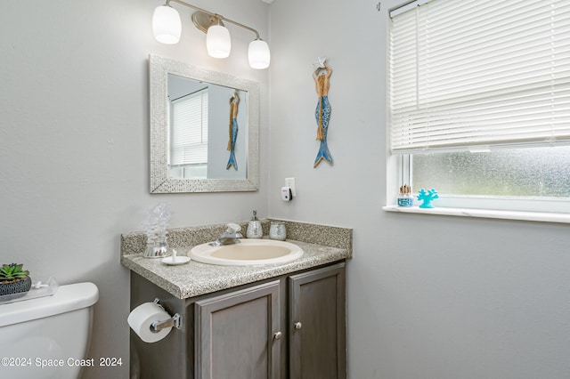 bathroom featuring vanity, plenty of natural light, and toilet