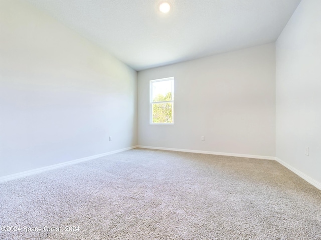 carpeted empty room with lofted ceiling