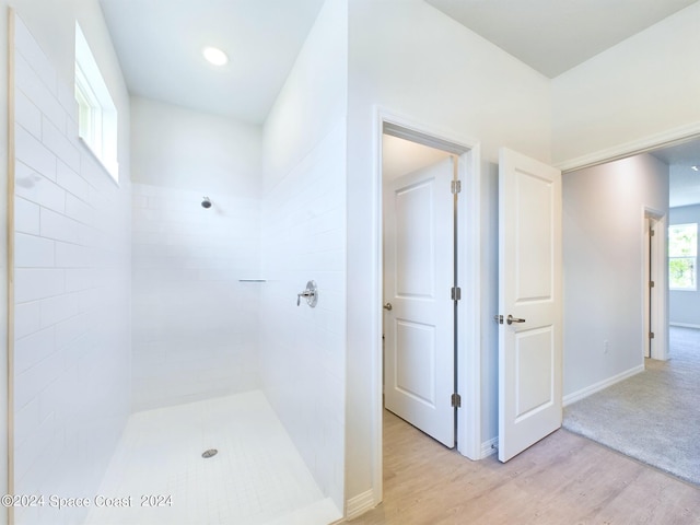 bathroom with hardwood / wood-style flooring and a tile shower