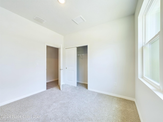 unfurnished bedroom featuring light colored carpet and a closet