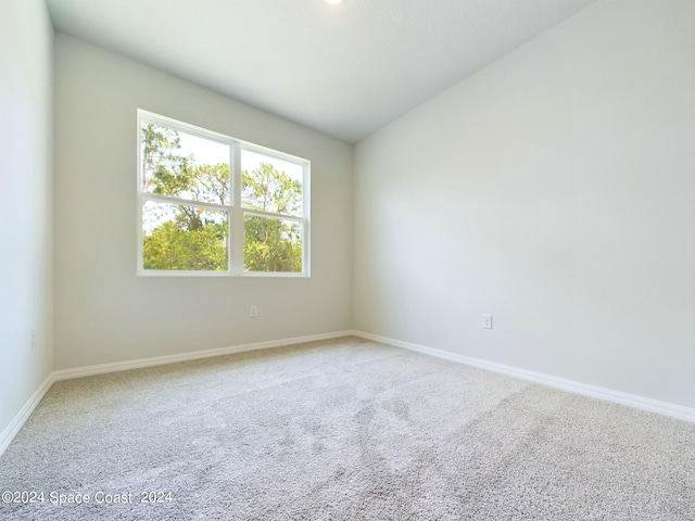 empty room with vaulted ceiling and carpet flooring