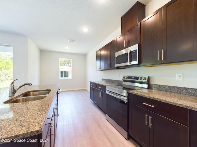 kitchen featuring appliances with stainless steel finishes, a healthy amount of sunlight, light hardwood / wood-style floors, and sink