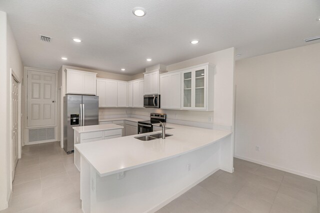 kitchen featuring a breakfast bar, sink, white cabinetry, appliances with stainless steel finishes, and kitchen peninsula