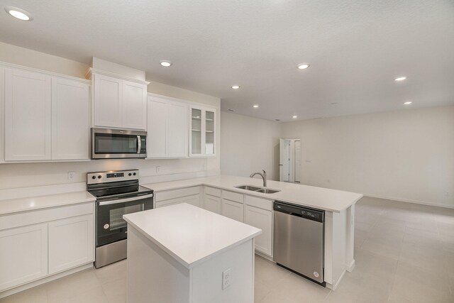 kitchen with white cabinetry, stainless steel appliances, a center island, and sink