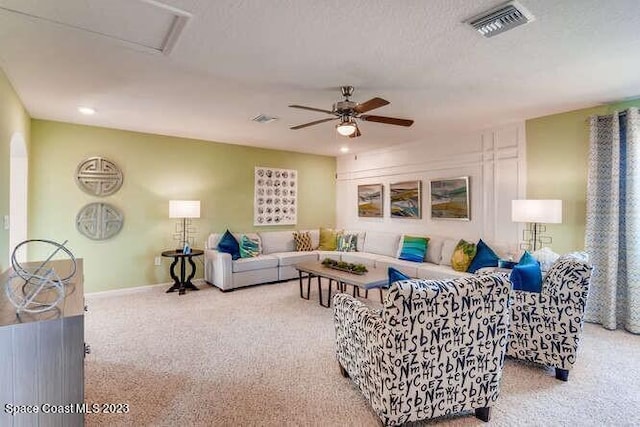 living room with a textured ceiling, ceiling fan, and light colored carpet